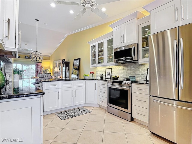 kitchen with appliances with stainless steel finishes, vaulted ceiling, ornamental molding, and light tile patterned floors