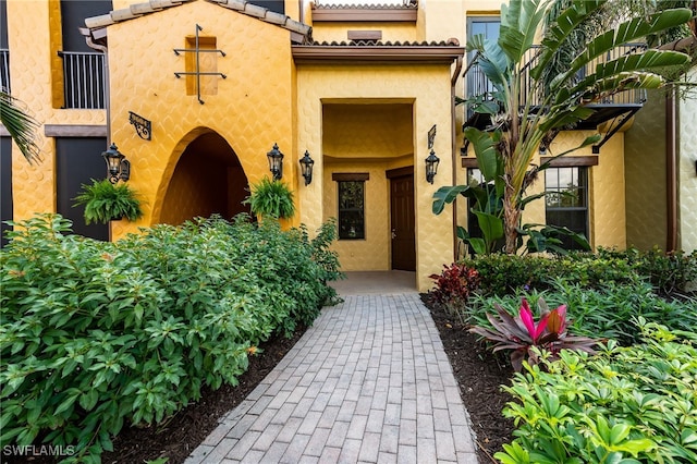 doorway to property with a tile roof and stucco siding