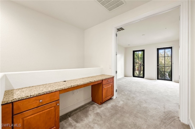 unfurnished office with light carpet, built in study area, and visible vents