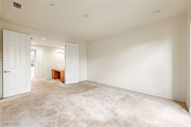 spare room featuring baseboards, ornamental molding, visible vents, and light colored carpet