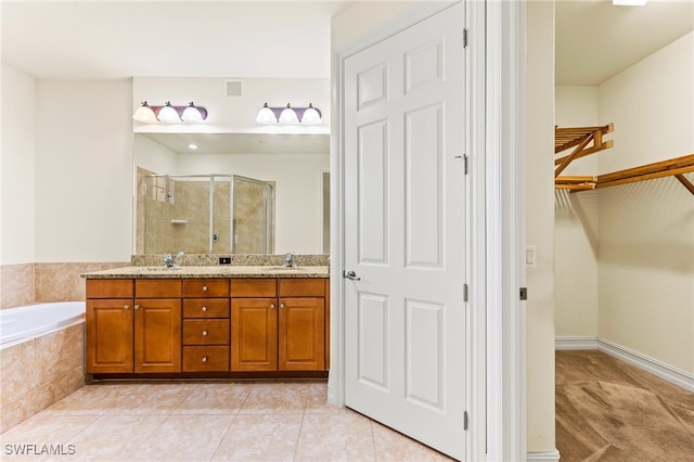 bathroom with a walk in closet, a sink, a shower stall, tile patterned flooring, and a bath