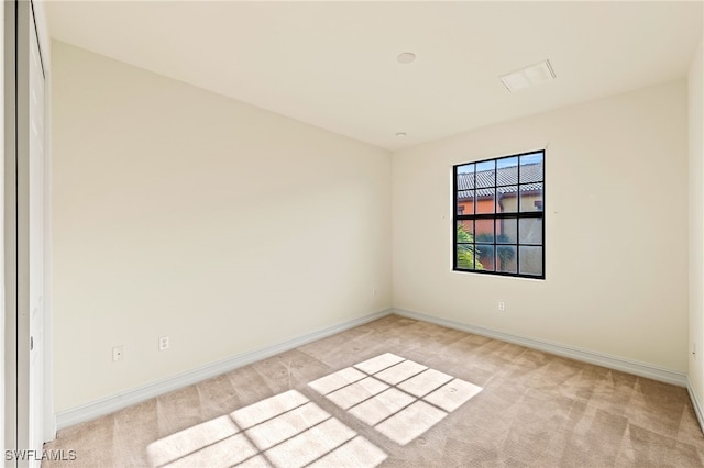 unfurnished room featuring light carpet and baseboards