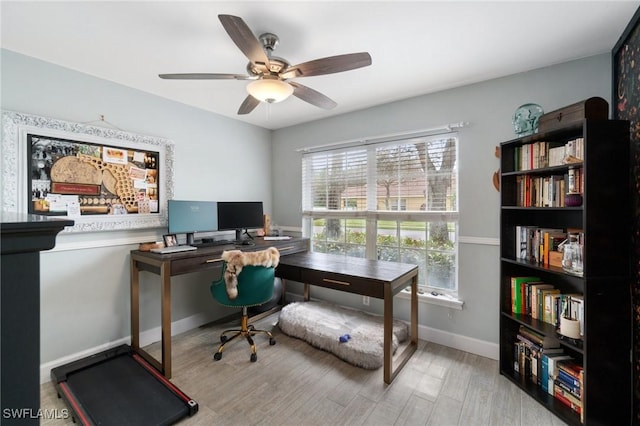 office space featuring baseboards, ceiling fan, and light wood finished floors