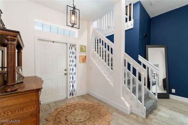 entrance foyer featuring light wood-type flooring, a high ceiling, baseboards, and stairs