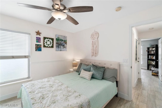 bedroom featuring multiple windows, light wood-style flooring, and baseboards