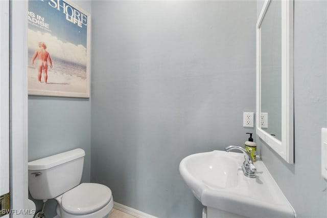 bathroom featuring toilet, baseboards, and a sink