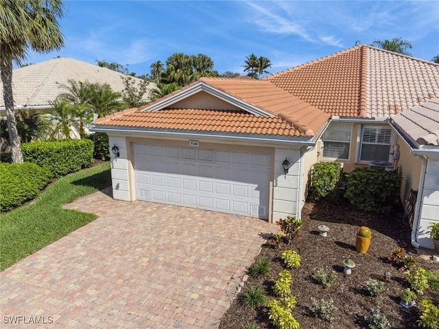 mediterranean / spanish-style home featuring a garage, driveway, a tile roof, and stucco siding