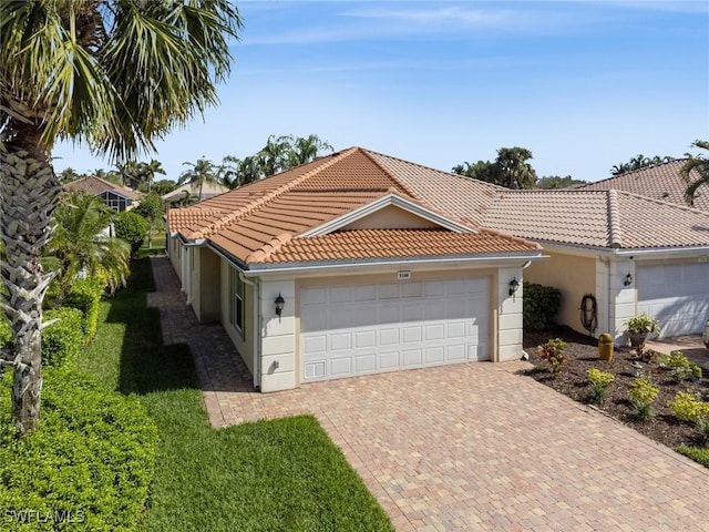 view of front of home featuring a garage, a tile roof, decorative driveway, and stucco siding