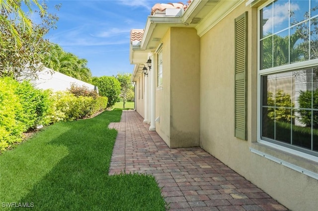 view of property exterior with a patio area, a yard, a tiled roof, and stucco siding