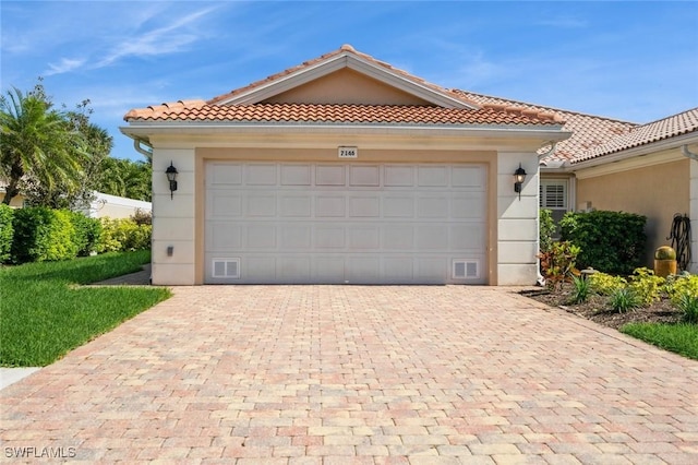 view of front of house featuring a garage, a tiled roof, decorative driveway, and stucco siding