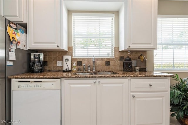 kitchen featuring tasteful backsplash, white cabinets, dishwasher, and a sink