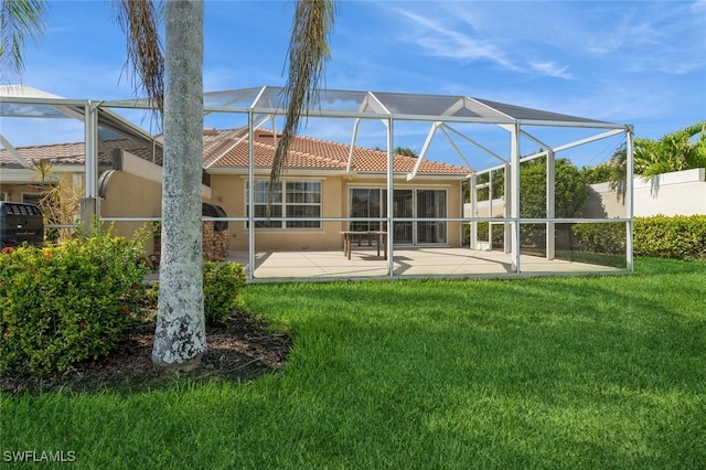 rear view of house featuring glass enclosure, a tiled roof, a lawn, stucco siding, and a patio area