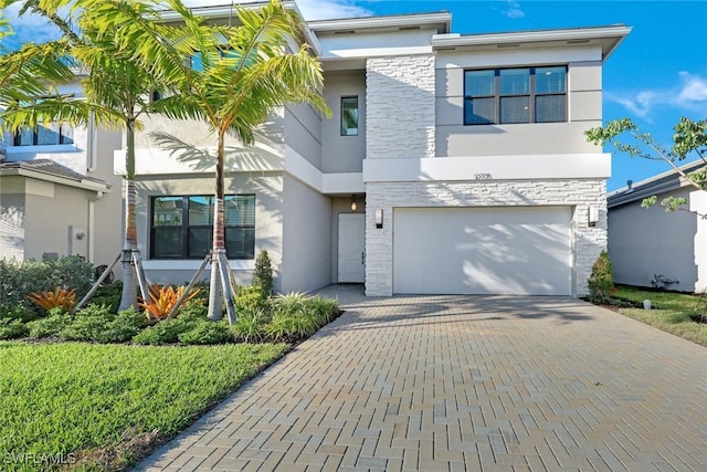 view of front of home featuring stucco siding, stone siding, an attached garage, and decorative driveway