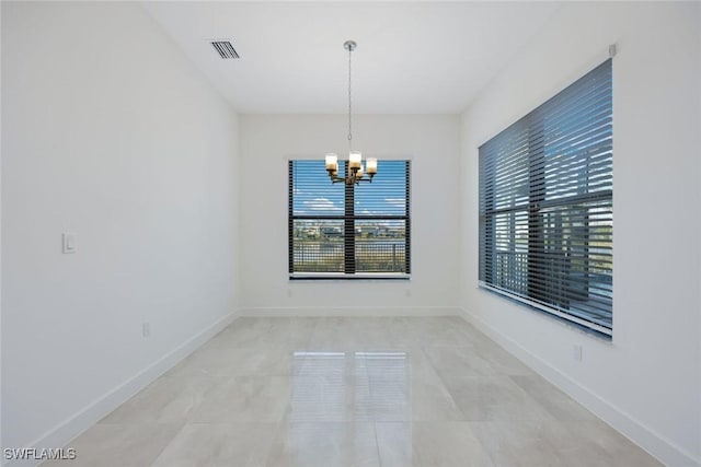 unfurnished room with a notable chandelier, visible vents, and baseboards