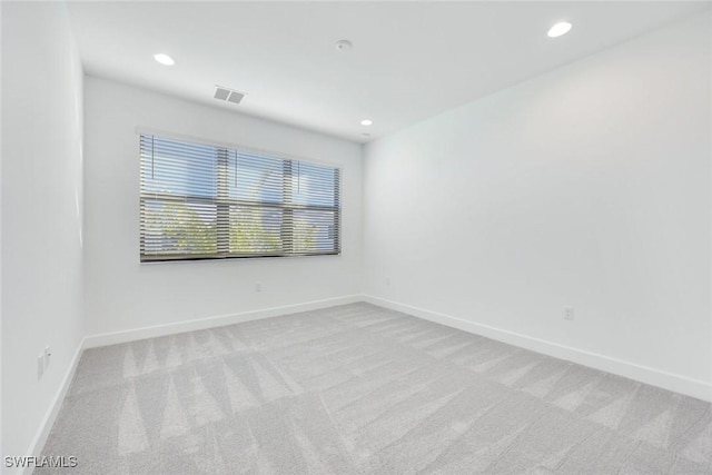 unfurnished room with light carpet, visible vents, recessed lighting, and baseboards