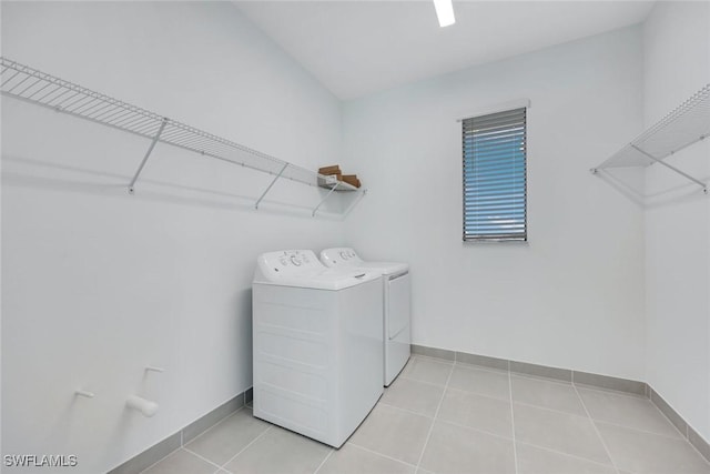 washroom with laundry area, light tile patterned floors, washing machine and dryer, and baseboards