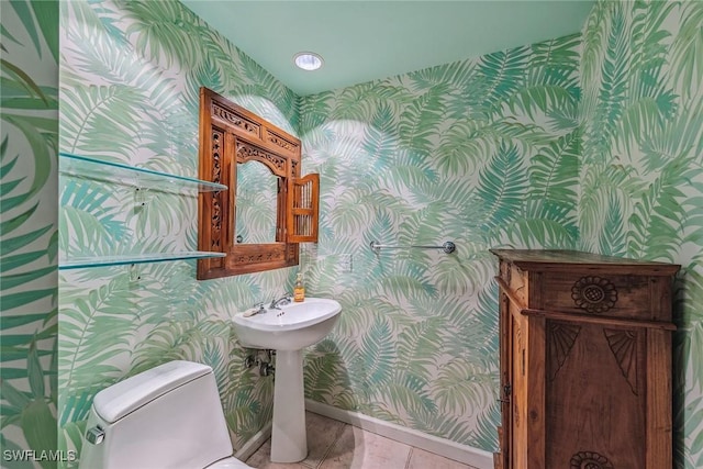 half bath with toilet, wallpapered walls, and baseboards