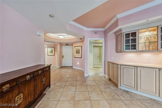 hallway featuring ornamental molding, a raised ceiling, and baseboards