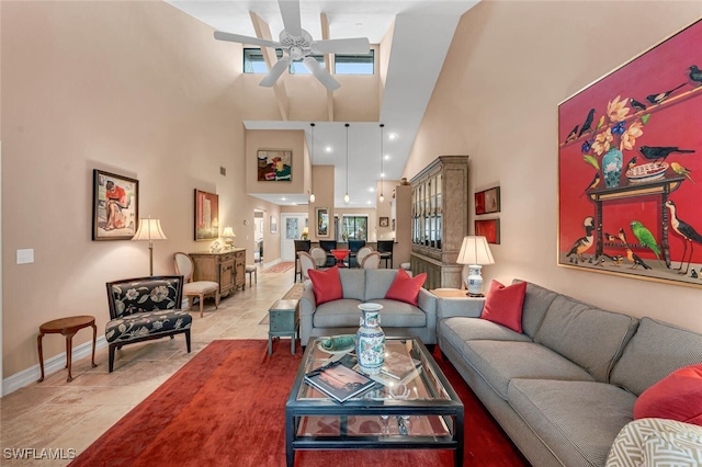 living area with ceiling fan, a towering ceiling, and baseboards