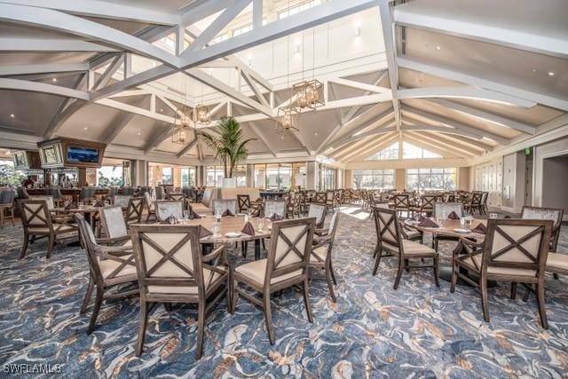 dining room with a wealth of natural light, vaulted ceiling with beams, carpet, and an inviting chandelier