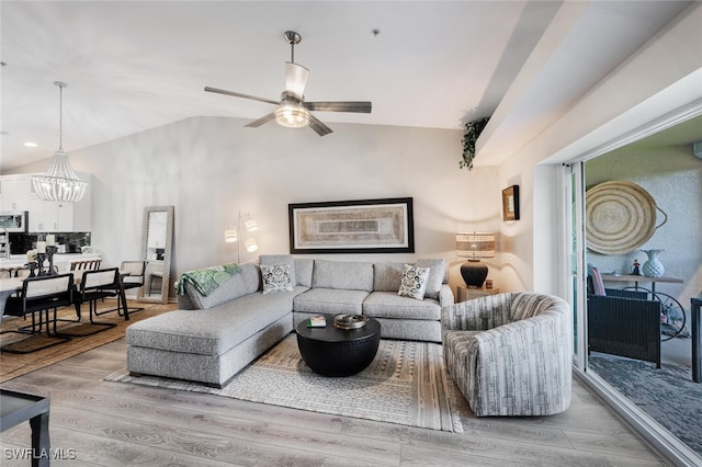 living room featuring light wood-style flooring, vaulted ceiling, and ceiling fan with notable chandelier