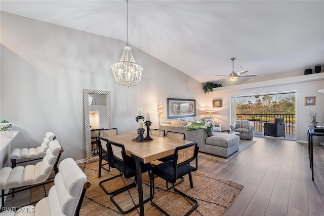 dining space with high vaulted ceiling, ceiling fan with notable chandelier, baseboards, and wood finished floors