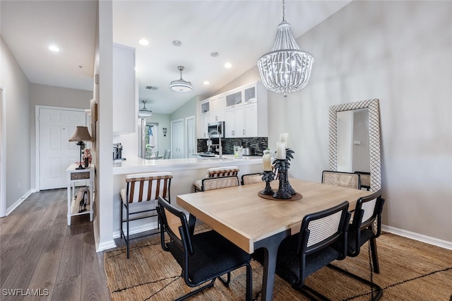 dining room with a notable chandelier, lofted ceiling, recessed lighting, wood finished floors, and baseboards