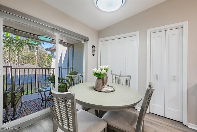 dining room with light wood-type flooring, baseboards, and lofted ceiling