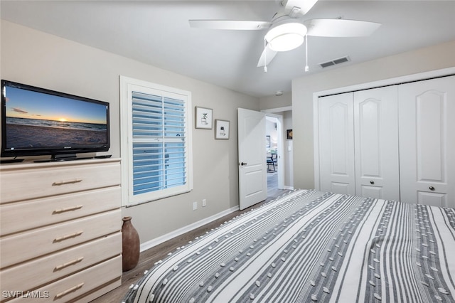 bedroom featuring dark wood-style flooring, a closet, visible vents, ceiling fan, and baseboards