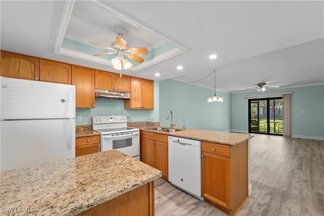 kitchen with under cabinet range hood, white appliances, a raised ceiling, and a sink