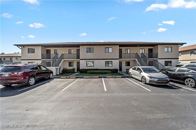 view of property with stairs and uncovered parking