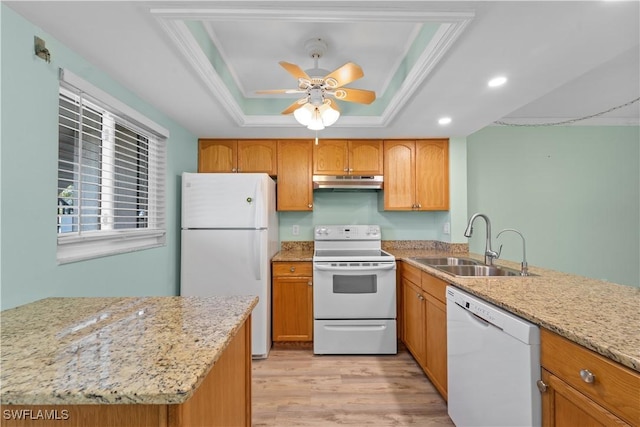 kitchen featuring under cabinet range hood, light wood-type flooring, a tray ceiling, white appliances, and a sink