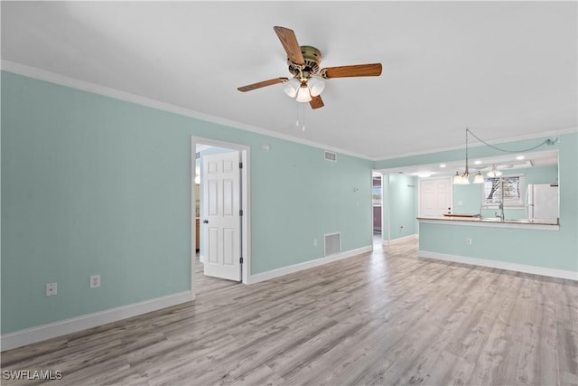 unfurnished living room featuring visible vents, baseboards, light wood-type flooring, ornamental molding, and ceiling fan with notable chandelier