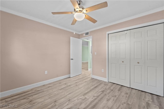 unfurnished bedroom with visible vents, ornamental molding, a closet, light wood-style floors, and baseboards