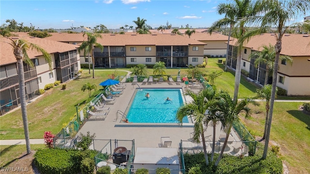 community pool featuring a yard, a residential view, a patio area, and fence