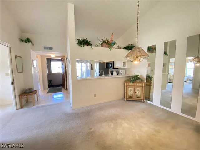 interior space with a high ceiling, visible vents, and carpet flooring