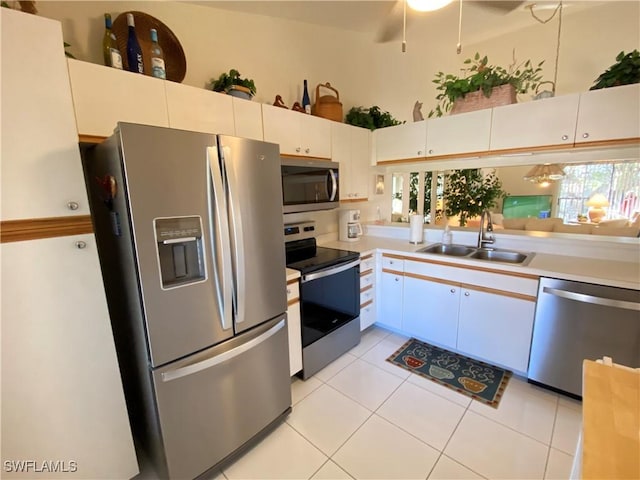 kitchen featuring light tile patterned floors, a sink, white cabinetry, light countertops, and appliances with stainless steel finishes