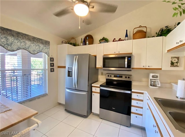 kitchen with stainless steel appliances, a sink, white cabinetry, vaulted ceiling, and light countertops