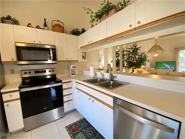 kitchen with decorative light fixtures, light countertops, appliances with stainless steel finishes, white cabinetry, and a sink