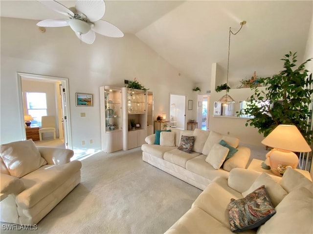 living area featuring high vaulted ceiling, a ceiling fan, and light colored carpet