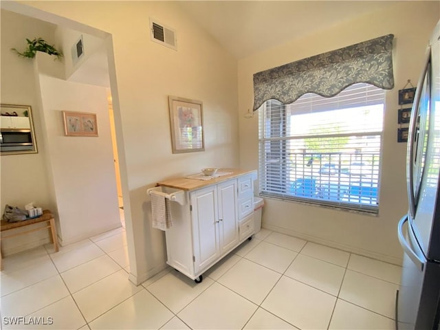 bathroom with tile patterned flooring, visible vents, and vaulted ceiling