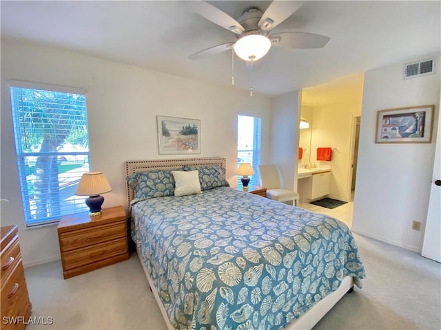 bedroom with light carpet, visible vents, baseboards, ensuite bath, and ceiling fan