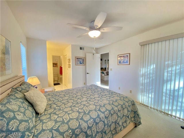 bedroom with light colored carpet, ceiling fan, visible vents, and ensuite bathroom