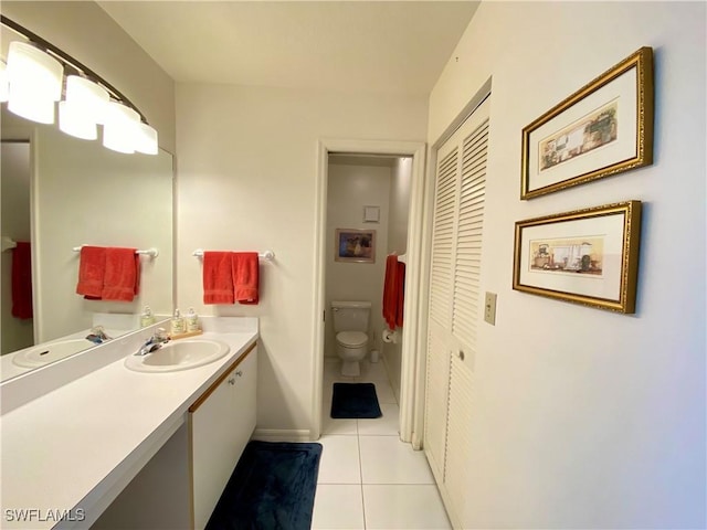 bathroom featuring a closet, toilet, vanity, baseboards, and tile patterned floors