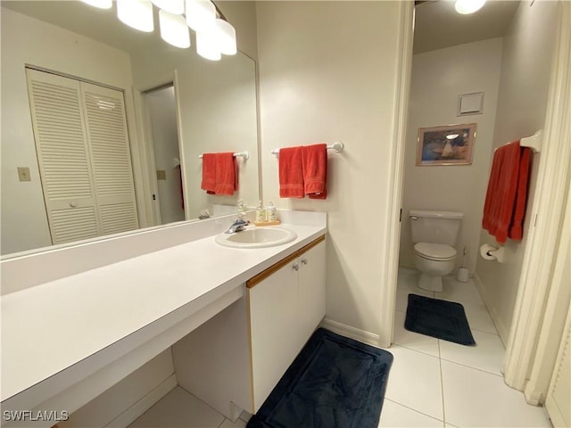 bathroom with a closet, toilet, vanity, baseboards, and tile patterned floors