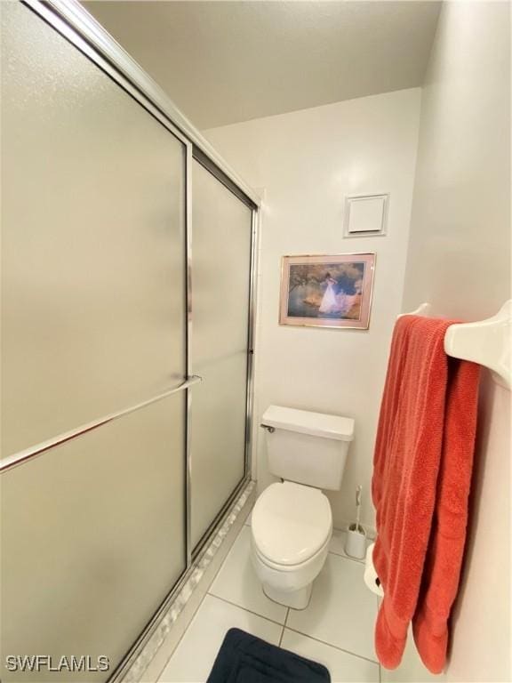 bathroom with tile patterned flooring, a shower stall, and toilet