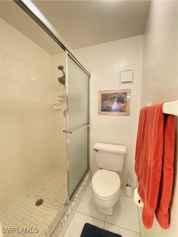 full bath featuring toilet, tile patterned flooring, and a shower stall