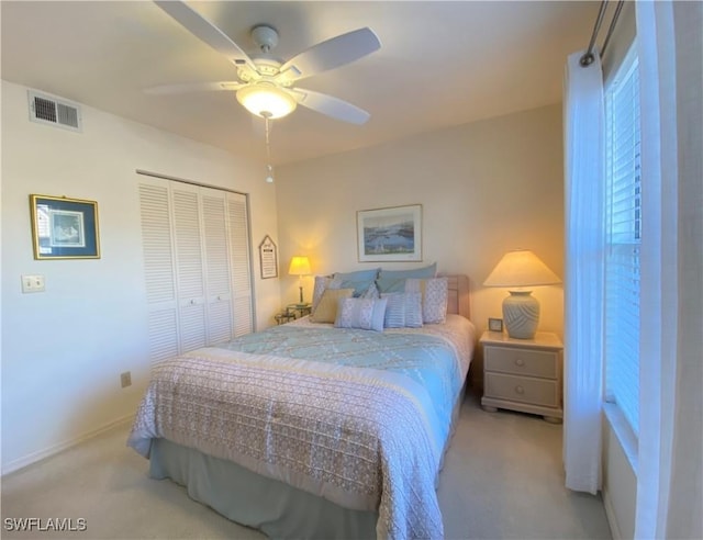 bedroom with light carpet, visible vents, baseboards, a ceiling fan, and a closet