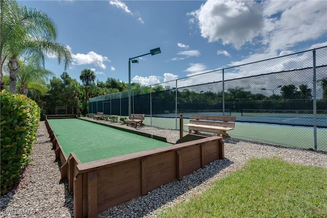 view of home's community with a tennis court and fence