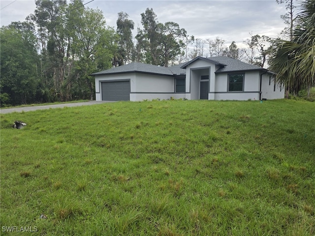 prairie-style home featuring driveway, stucco siding, an attached garage, and a front yard